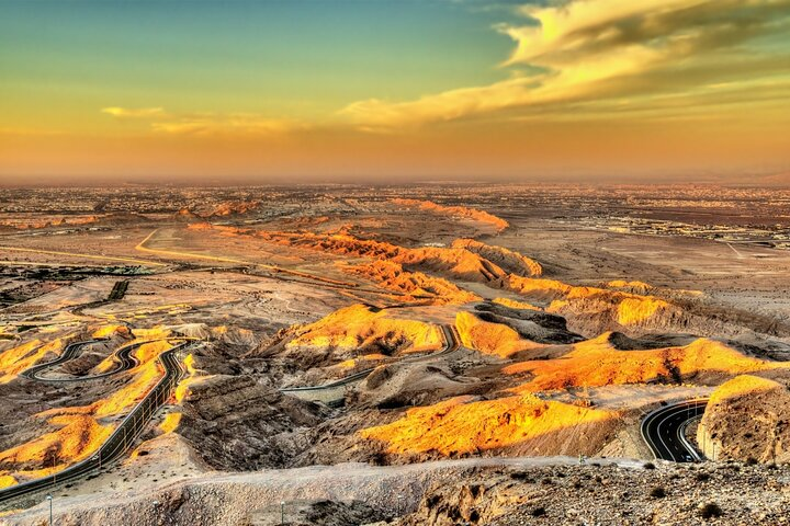 Experience the stunning landscapes of Al Ain where golden hues meet winding roads inviting endless exploration and a glimpse into the rich culture of the UAE.
